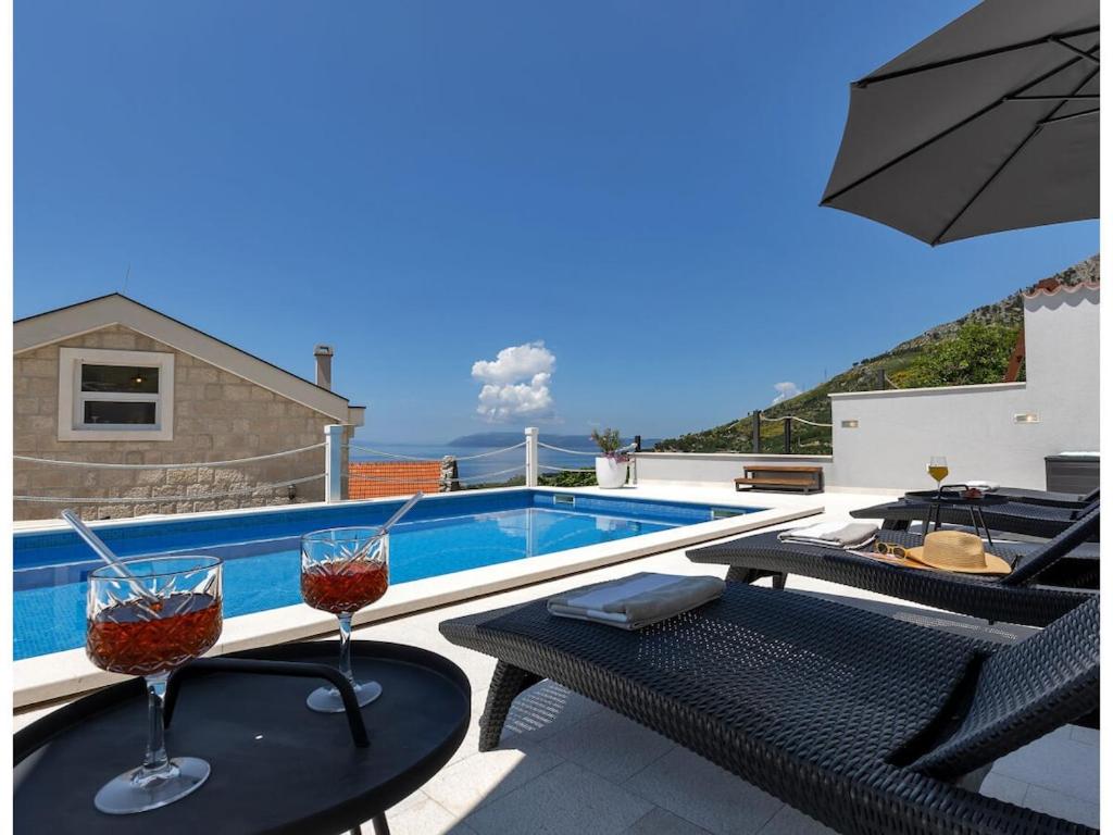 two glasses of wine sitting on tables next to a swimming pool at Rustic Villa Nina Tucepi in Tučepi