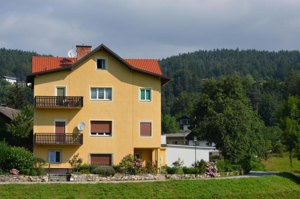 a yellow house with a balcony on a hill at Villa Wurzer in Velden am Wörthersee