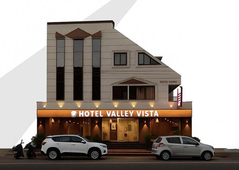 Dos coches aparcados delante de un hotel valley usa en Hotel Valley Vista, en Visakhapatnam