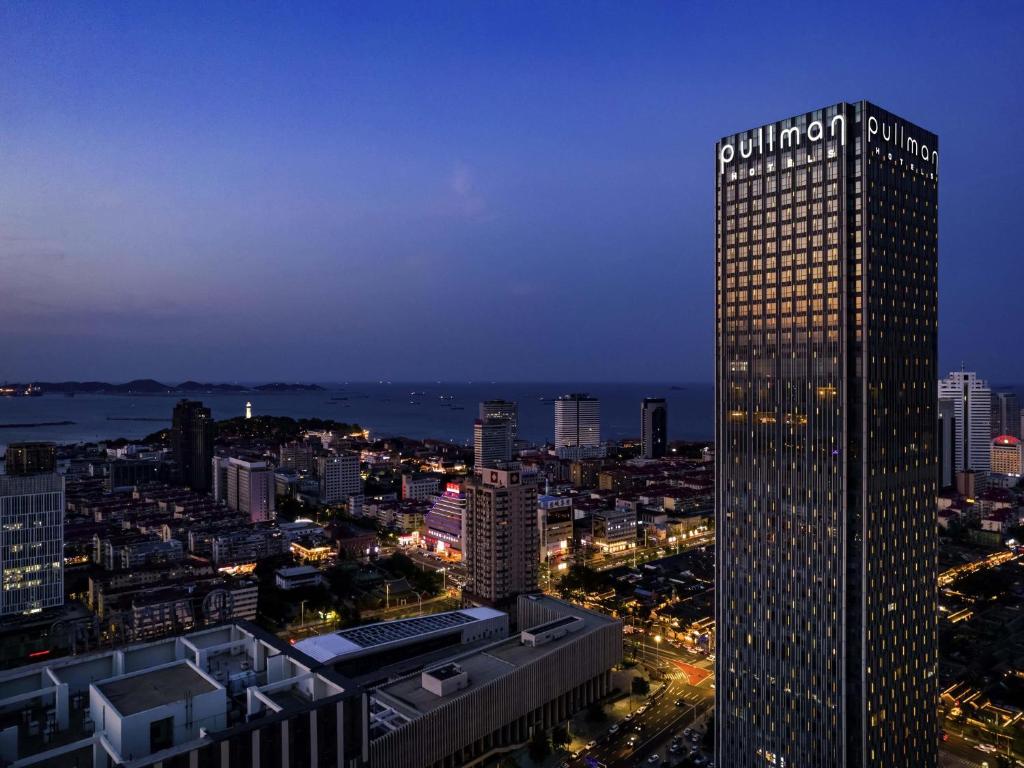 a tall building in a city at night at Pullman Yantai Center in Yantai