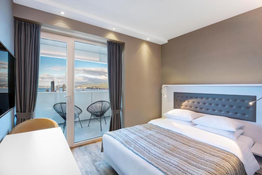 una habitación de hotel con una cama y un balcón en Alliance Palace In Batumi, en Batumi