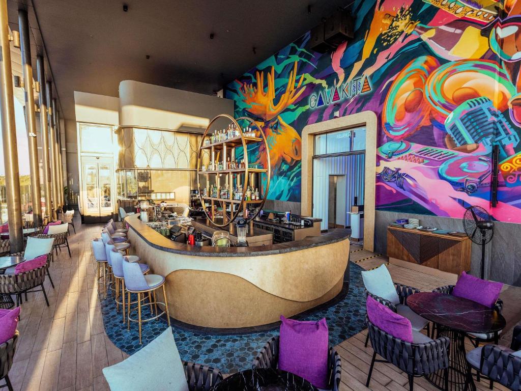 a restaurant with a bar with a colorful wall at Mercure Miri City Centre in Miri