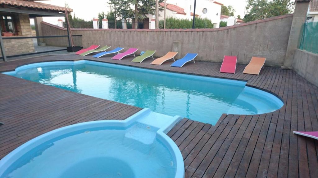 a swimming pool with colorful lounge chairs next to it at Hotel Rural Los Abriles in El Toro