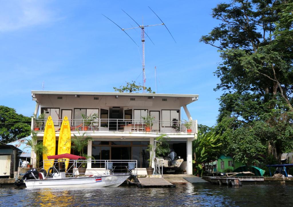 a boat is docked in front of a house on the water at Tortuguero Adventures GuestHouse in Tortuguero