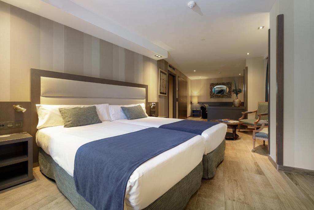Una habitación de hotel con una cama grande y una sala de estar. en Hotel Reina Cristina, en Teruel