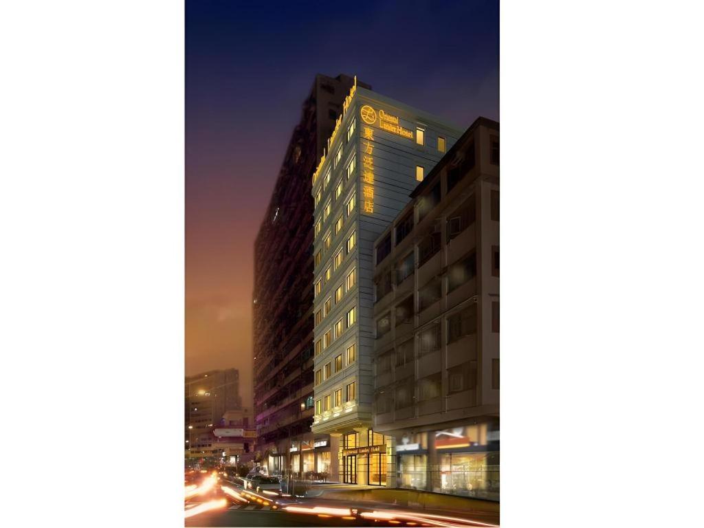 ein hohes Gebäude in einer Stadtstraße bei Nacht in der Unterkunft Oriental Lander Hotel in Hongkong