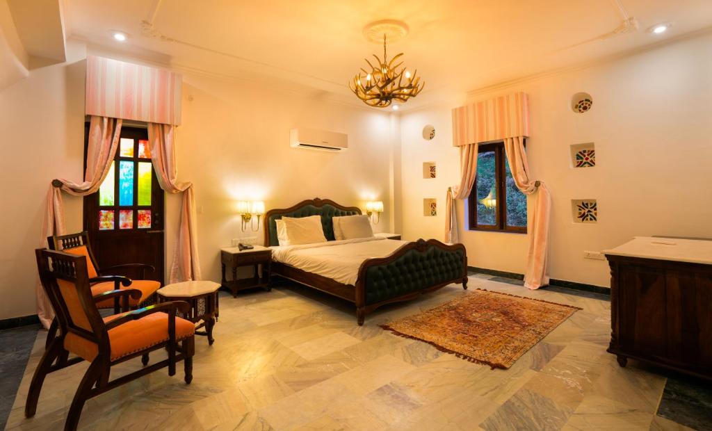a bedroom with a bed and a table and chairs at Medieval Forts & palaces in Pachār