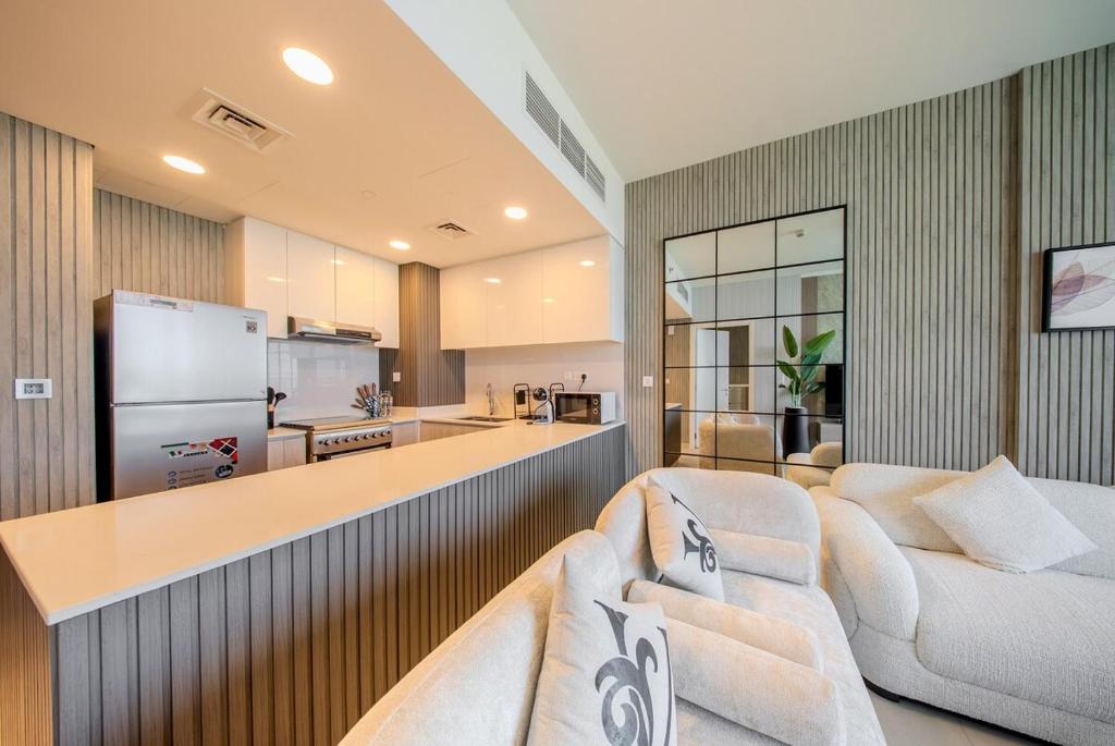 a living room with two white couches and a kitchen at 1BR Luxury Suite at Misk - Aljada Center - 2WC in Sharjah