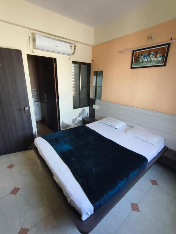 a bedroom with a large bed with a blue blanket at Hotel shivalay in Dwarka