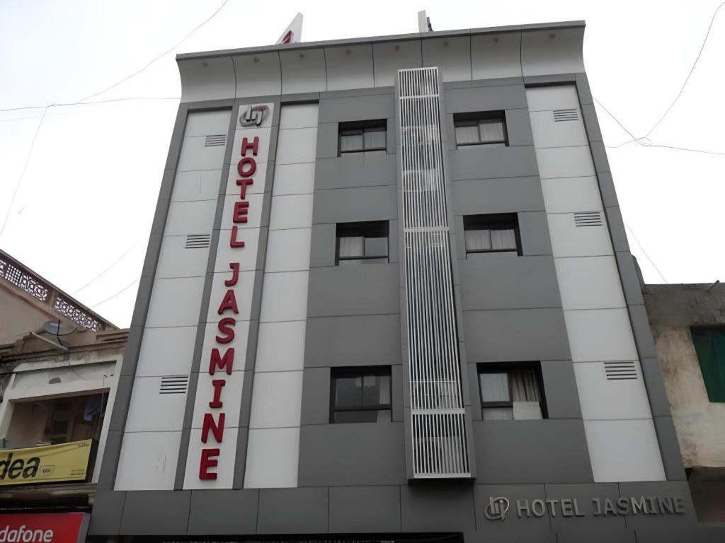 a tall white building with a red sign on it at Hotel Jasmine in Ahmedabad