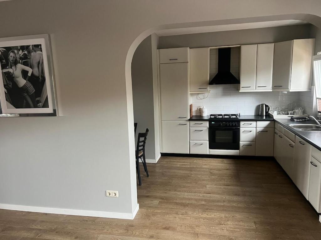Una cocina con gabinetes blancos y un horno de estufa. en Provence Driehuis Apartment, en Driehuis