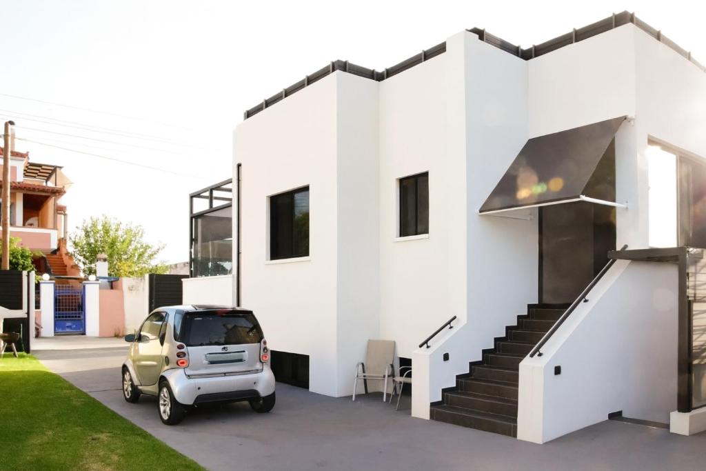 a small car parked in front of a white house at White & Black Aegina - Private Garden & Parking in Áyioi Asómatoi