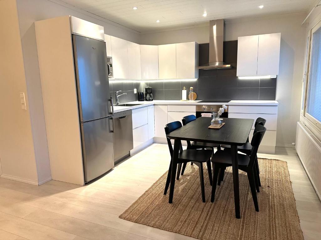 Una cocina con una mesa con sillas y un refrigerador. en Arctic Circle Holiday Homes, en Rovaniemi