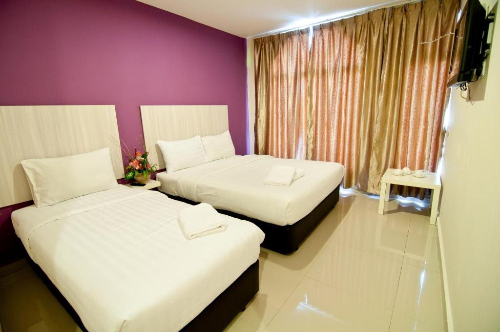 twee bedden in een kamer met een paarse muur bij 101 Hotel Bangi in Bangi