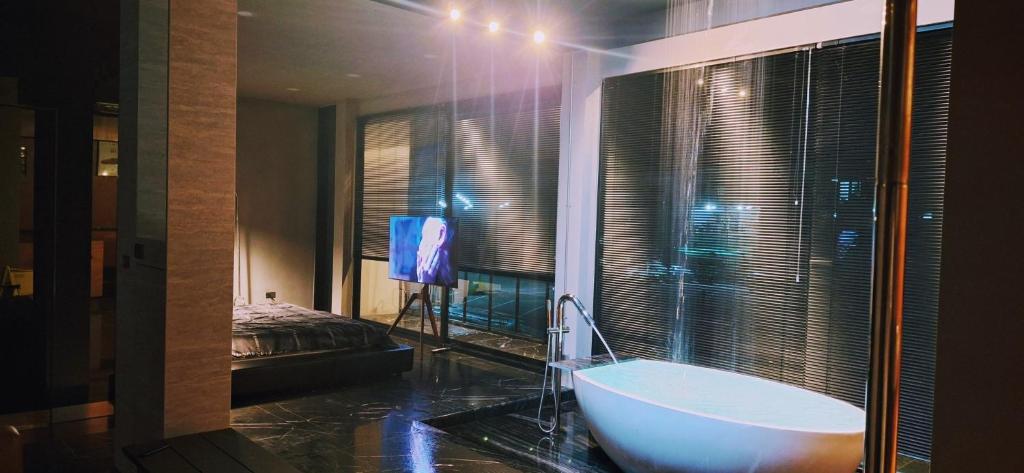 a bathroom with a tub and a tv in a room at Lanmuanghouse in Ban Pa Kluai