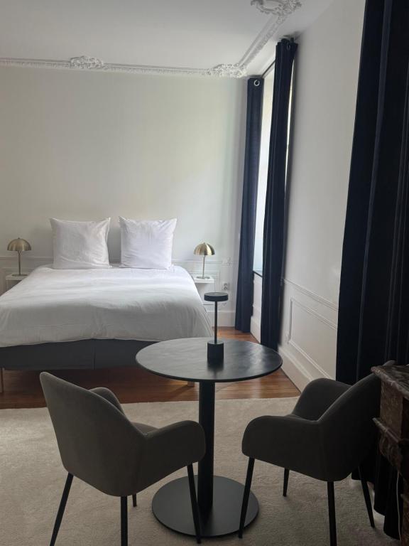 a bedroom with a bed and a table and chairs at La suite du parc 1 in Nancy