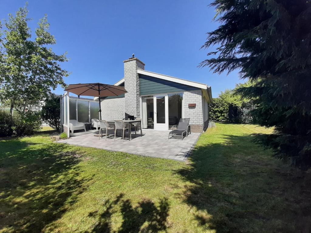 a house with a patio with chairs and an umbrella at Bungalow 024 in Petten