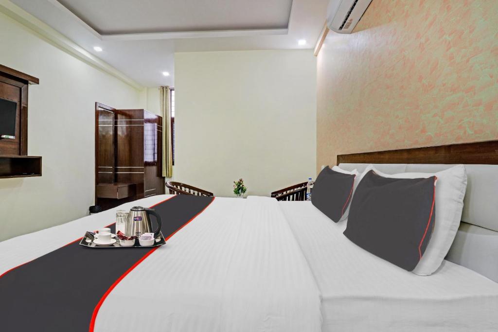 a bedroom with a large white bed with a red stripe at Hotel O Premnagar Heights in Jhājra