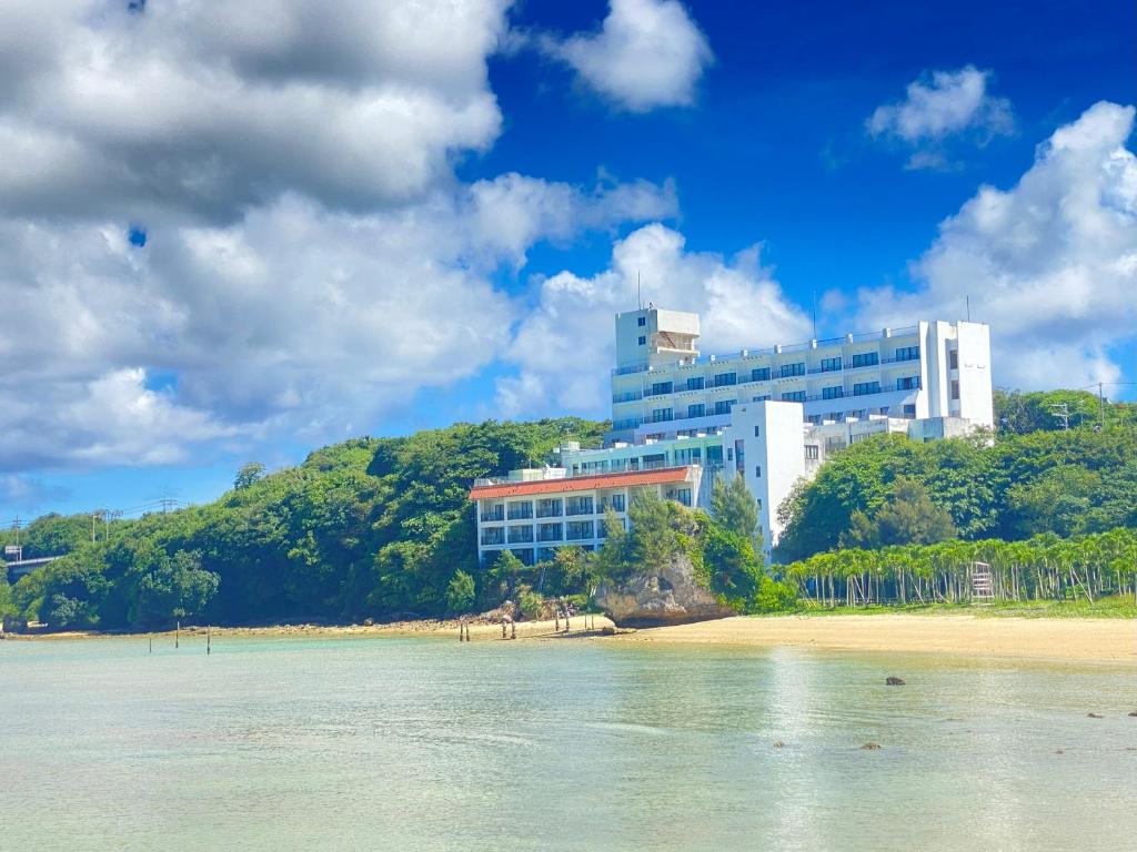a building sitting on top of a hill next to a beach at Churana Resort Motobu in Motobu