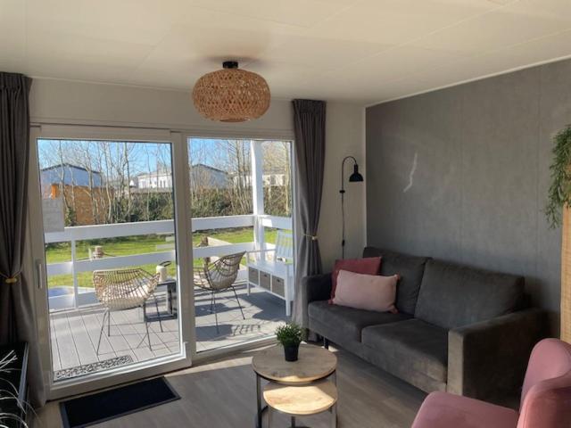 ein Wohnzimmer mit Sofa und Balkon in der Unterkunft J 013 in Petten
