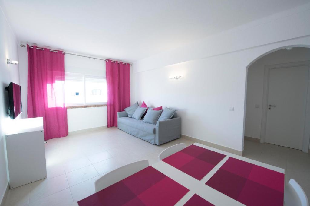 ein Wohnzimmer mit einem Sofa und einem roten Teppich in der Unterkunft Apartamentos Tio Papel II in Albufeira