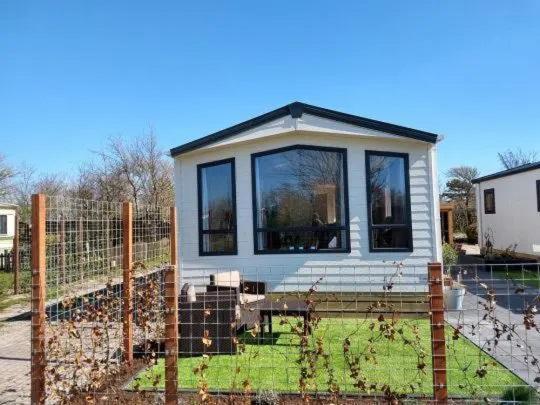 ein winziges Haus hinter einem Zaun in einem Garten in der Unterkunft J 019 in Petten