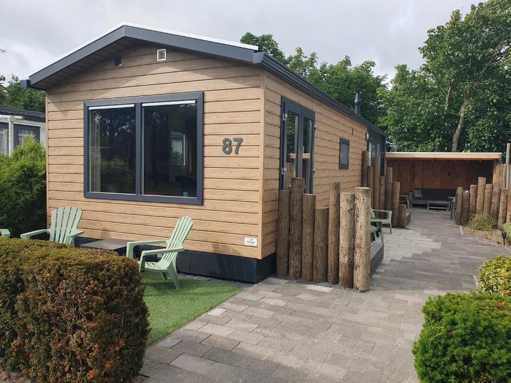 ein kleines Haus mit einer Terrasse in einem Garten in der Unterkunft Chalet 87 in Petten