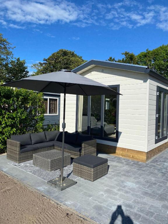 eine Terrasse mit Sofa und Sonnenschirm in der Unterkunft J121 in Petten