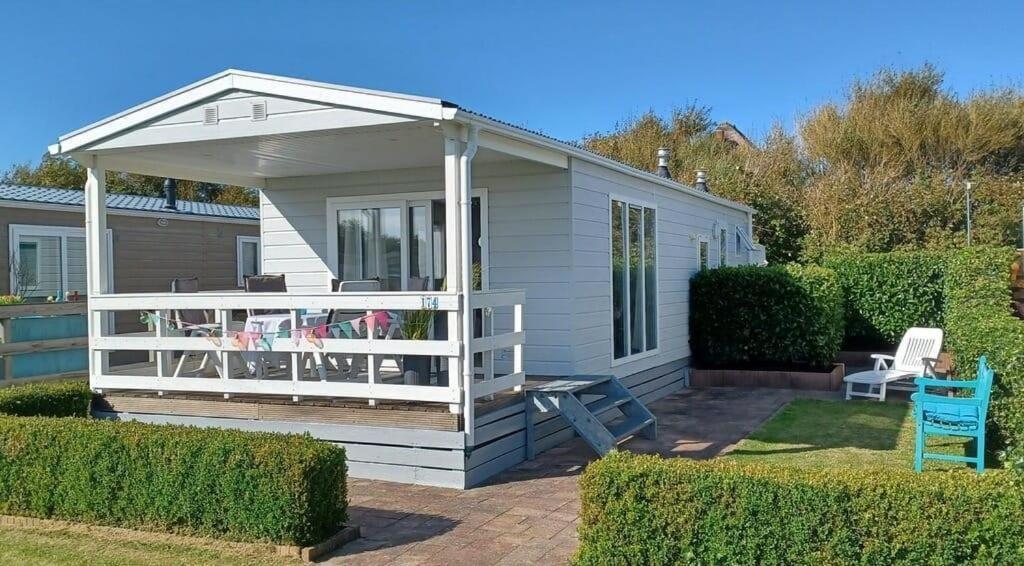 ein weißes kleines Haus mit einer Veranda und einer Terrasse in der Unterkunft J 174 in Petten