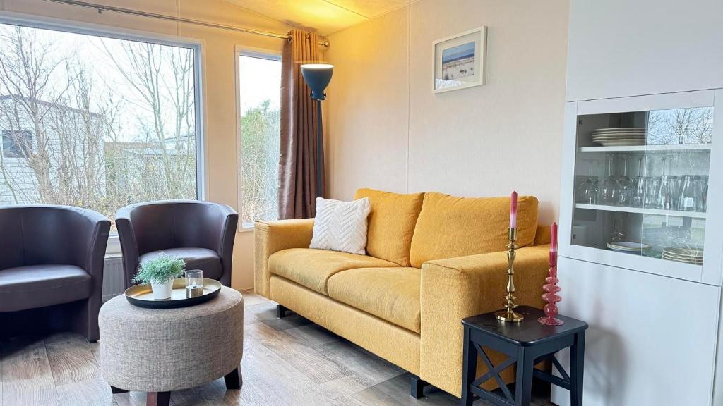 ein Wohnzimmer mit einem gelben Sofa und zwei Stühlen in der Unterkunft J 219 in Petten
