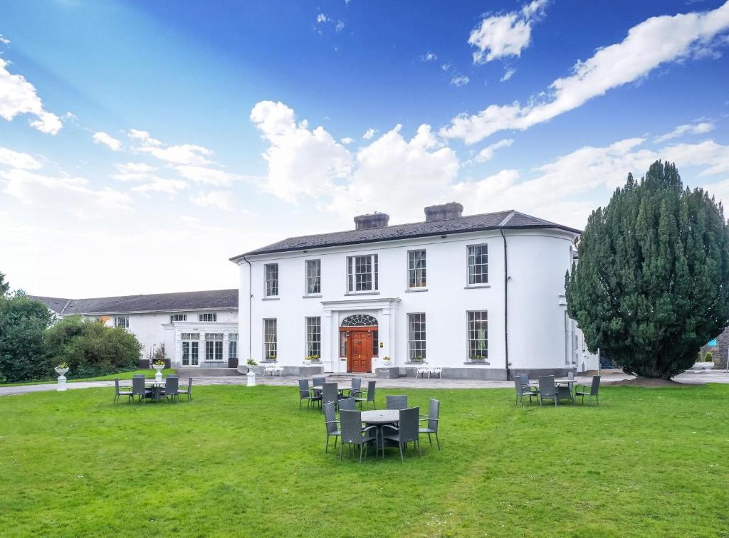 Un gran edificio blanco con mesas y sillas en el césped. en Springfort Hall Hotel, en Mallow