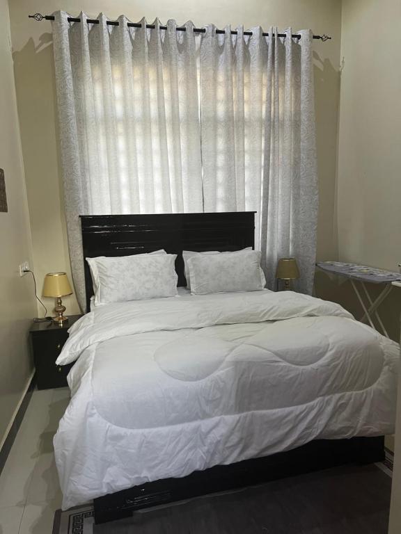 a bedroom with a large white bed with a window at Luna Apartment in Dodoma