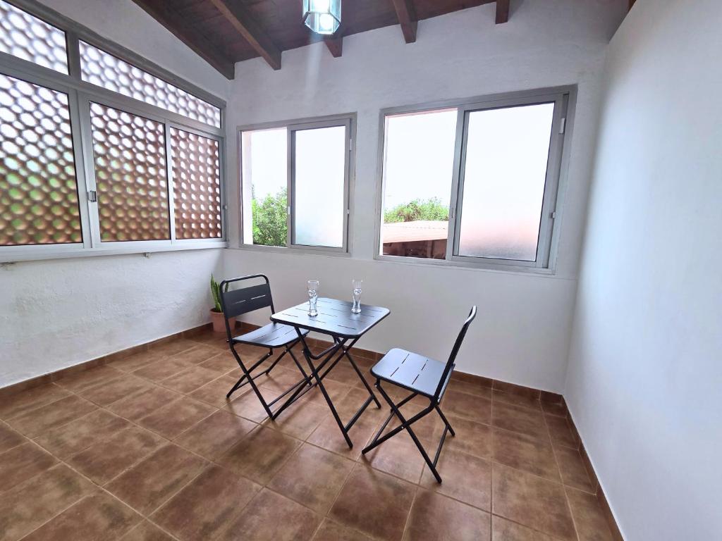 Una mesa y sillas en una habitación con ventanas. en Emelina, en La Guancha