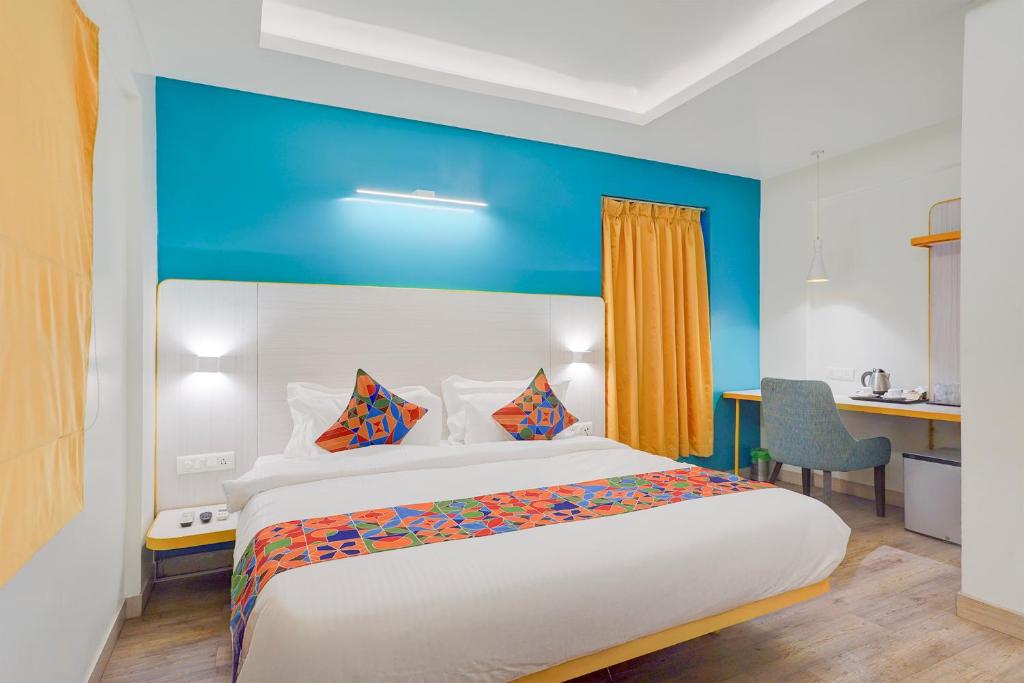 a bedroom with a large bed with a blue wall at FabHotel SLR Residency in Bengaluru