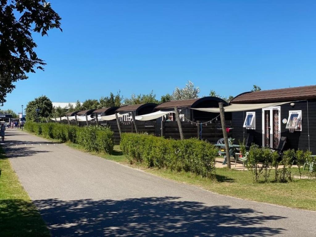 a row of houses with umbrellas on the side of a road at Kampeerwagon in Petten