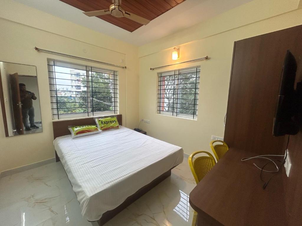 a bedroom with a bed and two windows at Hotel O R R Comforts Boarding and Lodging in Nelamangala