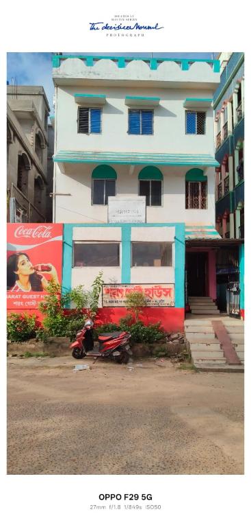 a white and blue building with a scooter in front of it at Sarat guest house in Digha