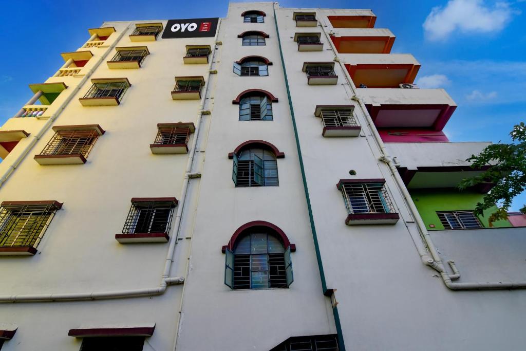 a tall white building with windows and balconies at Hotel O Lila Guest House in Sāntrāgāchi