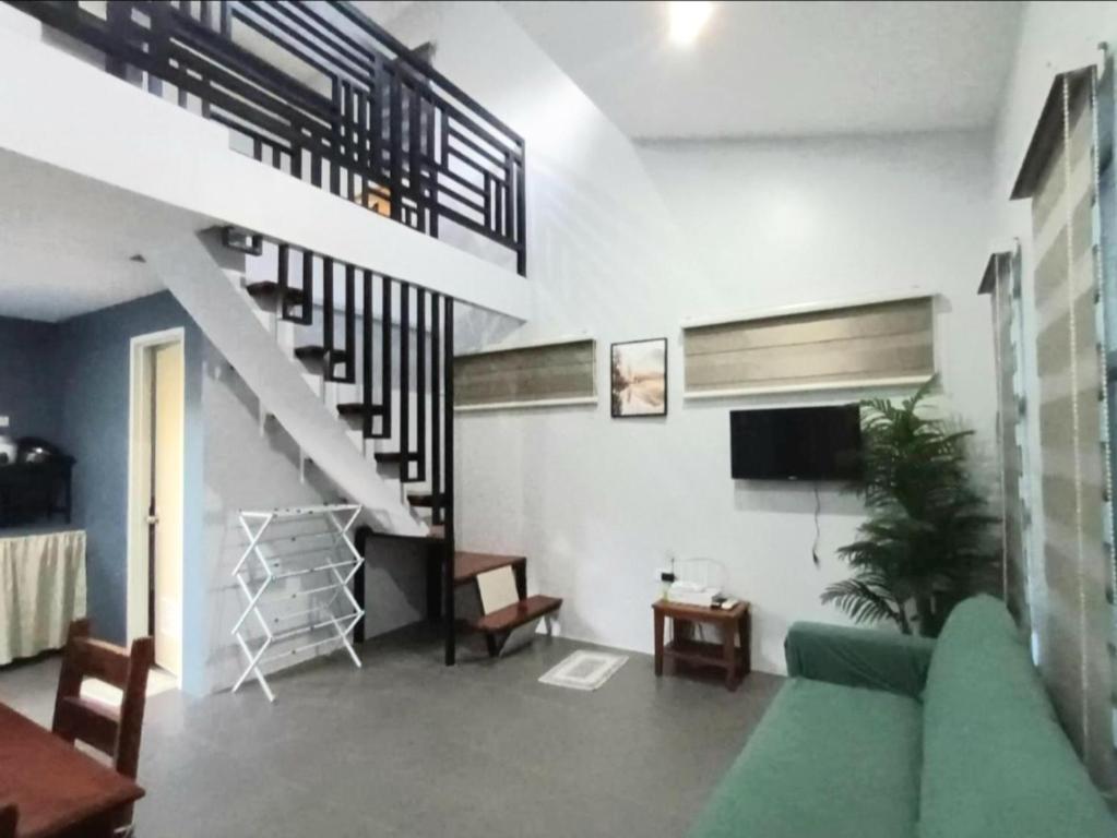 a living room with a couch and a staircase at Grae’s Apartelle in Moalboal