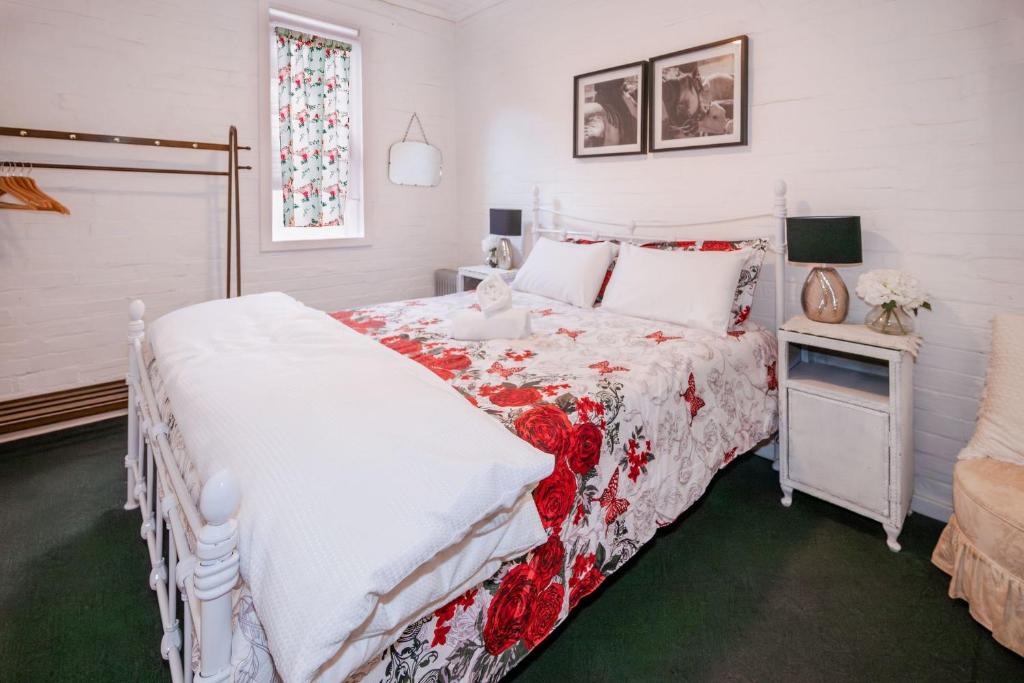 a bedroom with a bed with a red and white comforter at Bluebird Cottage in West Tamworth