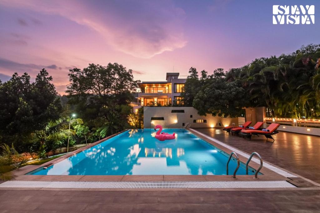 a villa with a swimming pool at night at StayVista at Anandam Lake Villa - Khadakwasla in Pune