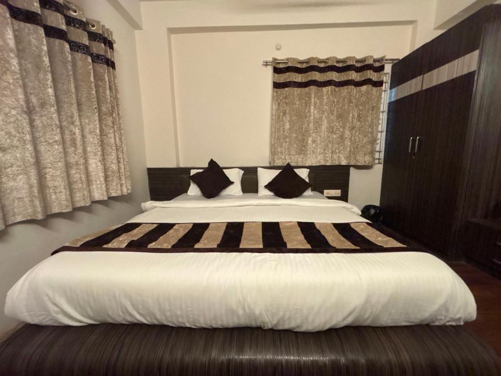 1 dormitorio con 1 cama blanca grande con almohadas negras en HOTEL O THE 9 CUBE, en Habībganj
