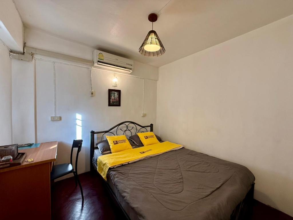 a bedroom with a bed with yellow pillows and a desk at Dengba Hostel - Loikroh Chiangmai in Ban Hua Phrong