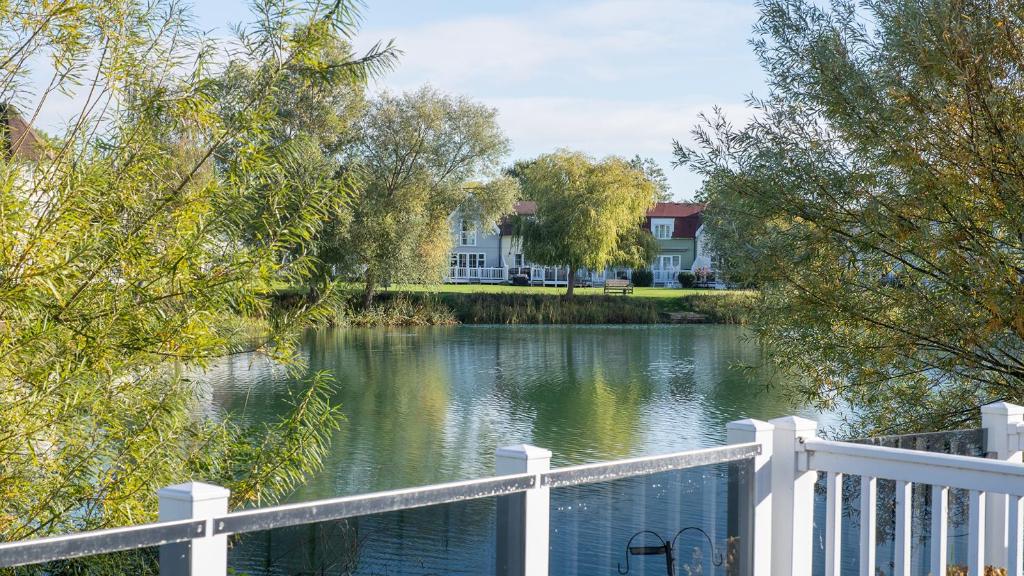 a white fence next to a river with a house at Venture Lakeside Lodge in South Cerney