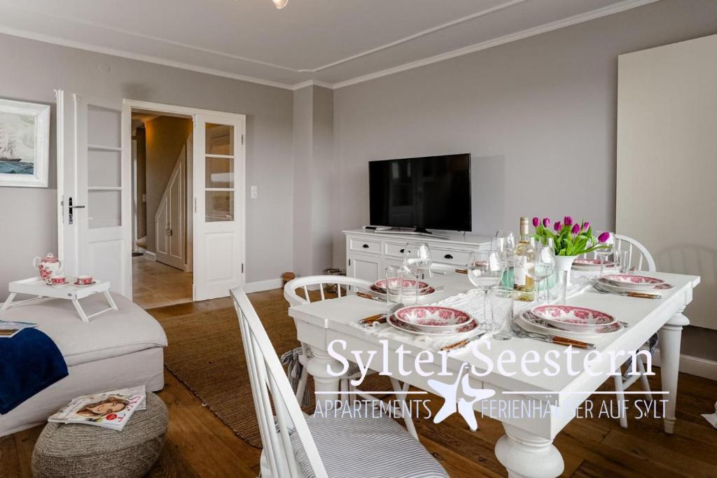 comedor con mesa blanca y TV en Sylter Seestern Haus Dorfglück, en Morsum