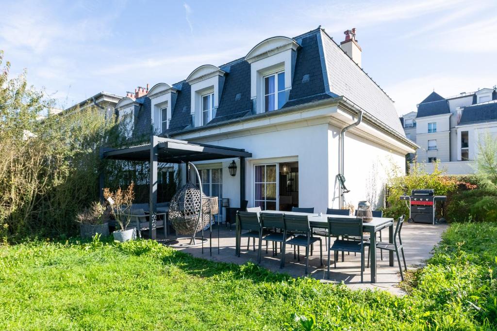 ein Haus mit einer Terrasse mit Tisch und Stühlen in der Unterkunft L'Elbe in Serris