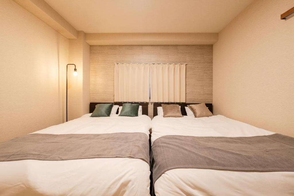 twee bedden in een kleine kamer met tweederde bij Terrace Tokyo Otsuka in Tokyo