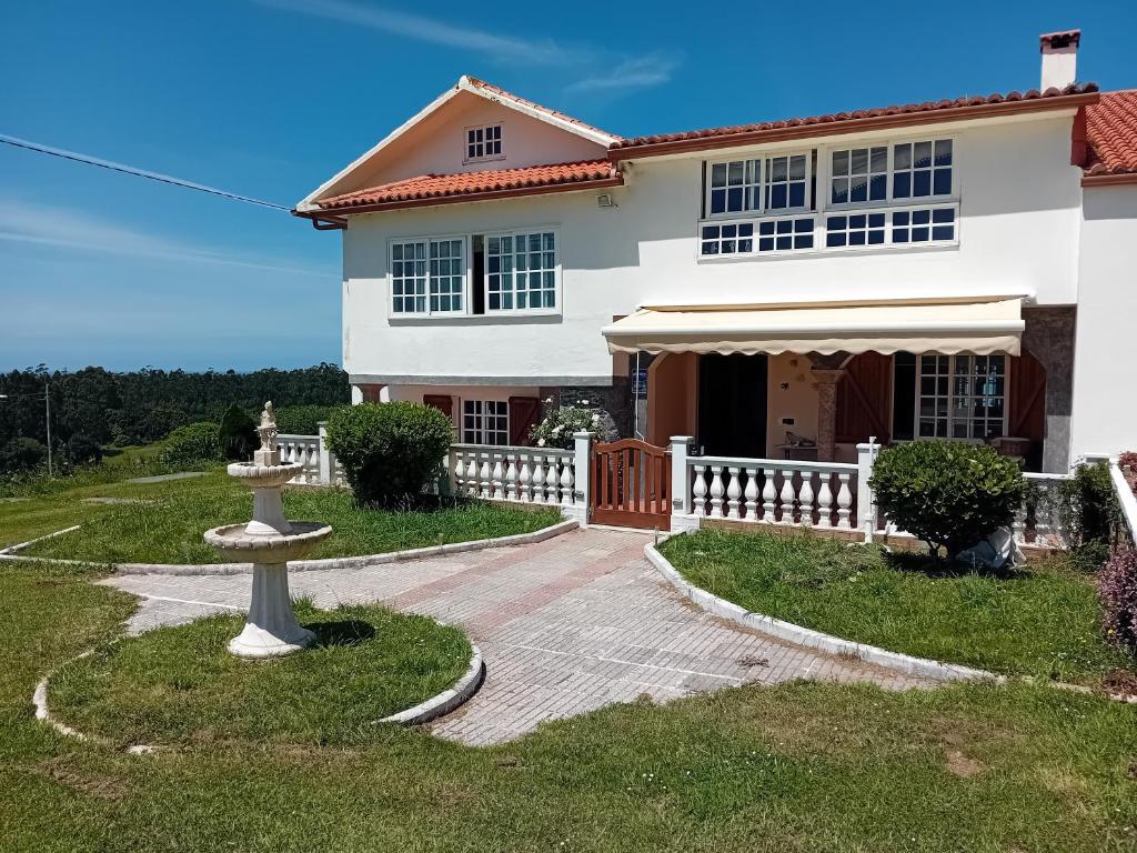 a white house with a fountain in front of it at Casa Corral Bouzamayor in Valdoviño