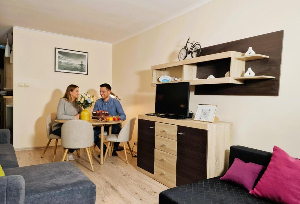 a man and woman sitting at a table in a living room at SeaShell Studio Przymorze in Gdańsk