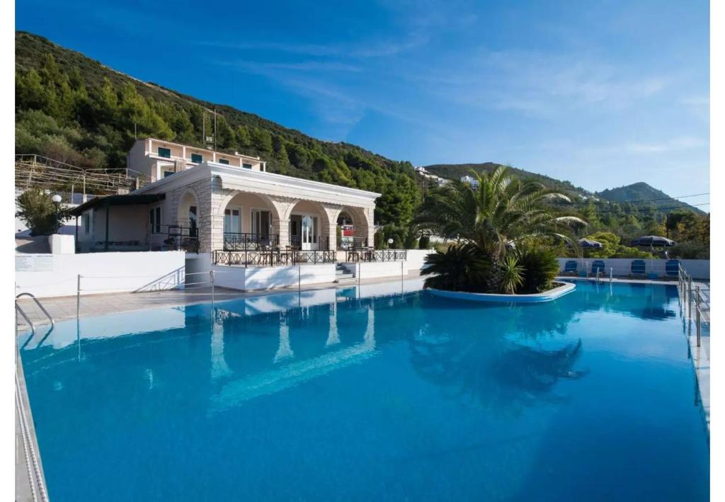 una gran piscina de agua azul frente a un edificio en Sunset Premium Studio 9, en Agios Nikitas